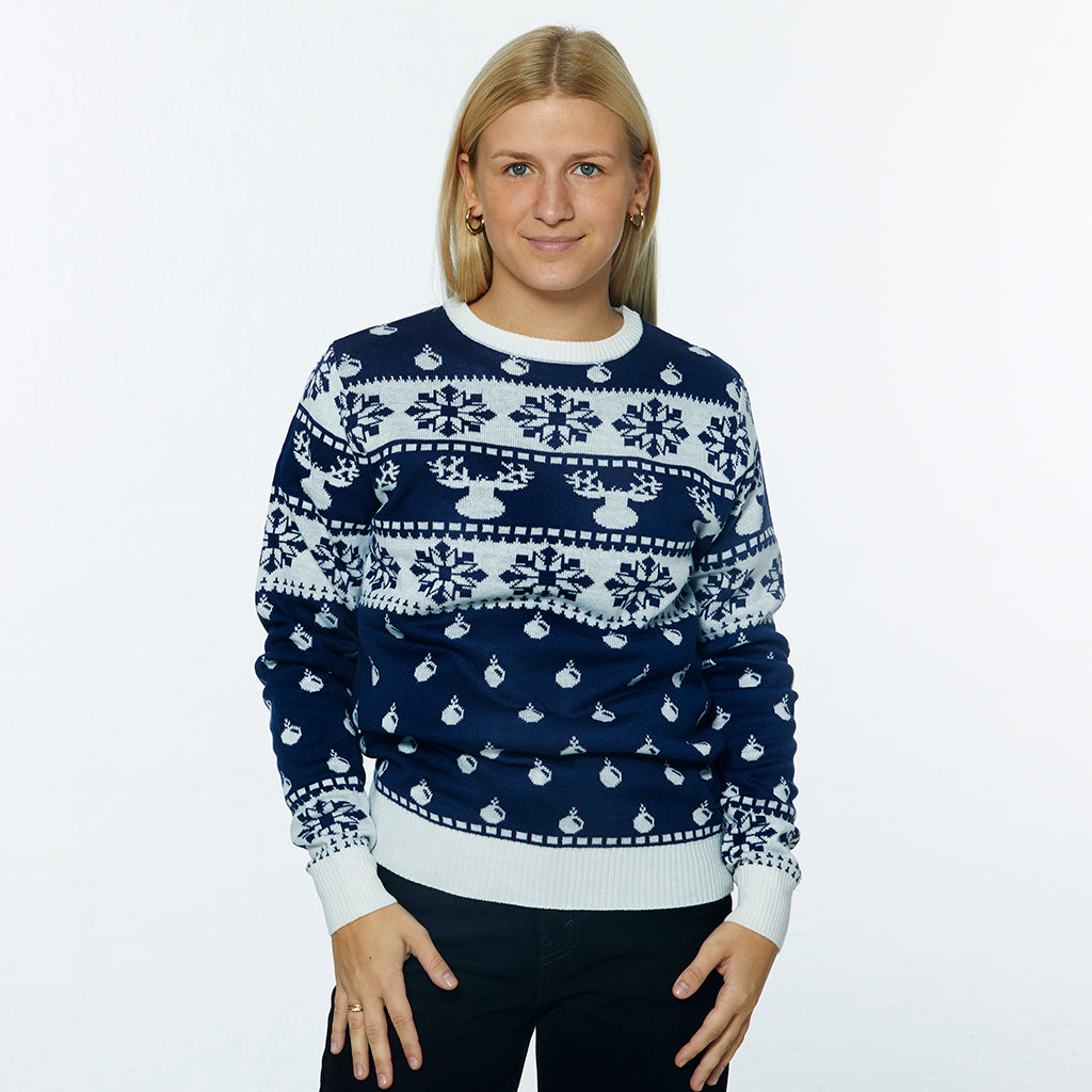 En kvinne poserer iført en blå julegenser med julemønster og reinsdyr på.